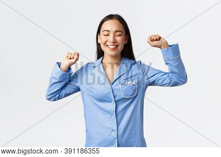 Smiling Joyful Asian Girl In Pajamas Standing With Closed Eyes And Delighted Grin, Stratching After 