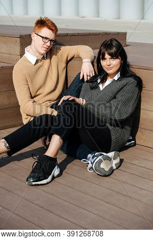 Young Couple Resting On Wooden Stairs Outdoors.