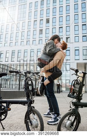 Side View Of A Man Kissing His Girl, Holding Her In Front By Her Thighs,