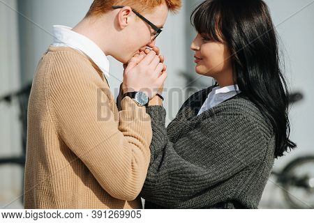 Caring Young Man Warming His Girlfriends Hands, Holding In Palms, Breathing In