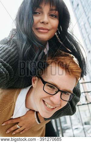 Young Man Holding His Girl On The Back. They Are Looking At Camera, Posing