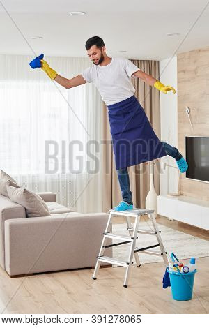 Man Having Fun While Climbing Ladder To Clean Ceiling. Cleaning Service Concept