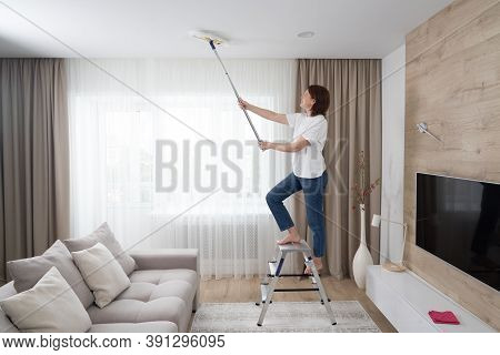 Woman Cleaning Ceiling With A Mop. Housewife Cleaning Living Room