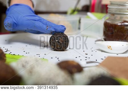 A Woman In Rubber Gloves Makes Candies From Dried Fruits And Nuts At Home In Self-isolation During A