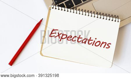 Laptop, Red Pen And Notepad With Text Expectations In The White Background