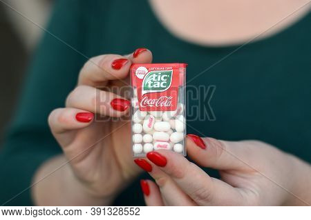 Young Girl Holds Tic-tac Hard Mints Pack With Coca-cola Taste. Tic Tac Is A Brand Of Small Hard Mint