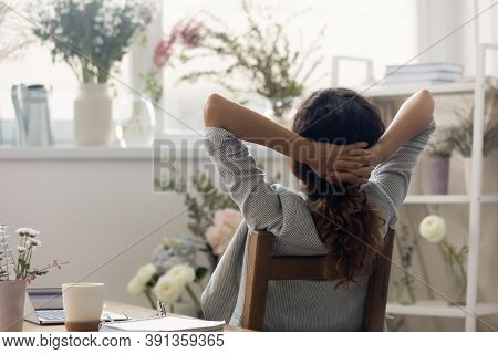 Back View Of Female Designer Relax In Chair At Workplace