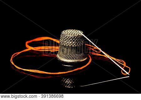 Needle With Thread And Thimble On A Black Background