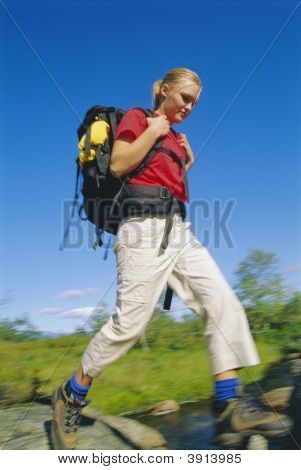 Kvinde hopper over klipperne på floden