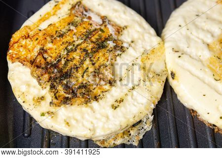 Delicious Pieces Of Halumi Cheese Cooking On A Hot Iron Stove With Smoke Coming Out
