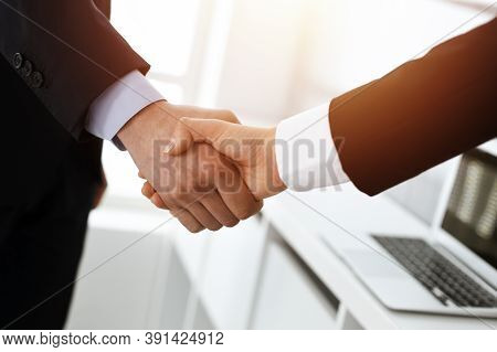 Businessman And Woman Shaking Hands In Sunny Office, Close-up. Concept Of Handshake As Success Symbo