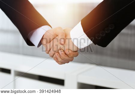 Businessman And Woman Shaking Hands In Sunny Office, Close-up. Concept Of Handshake As Success Symbo