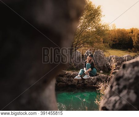 Wide Portrait Of An Attractive Brunette Sitting On A Well At The Rajcica Wells Natural Landmark. Gir