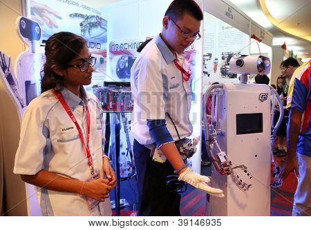 SUBANG JAYA - NOV 10: An unidentified student from Malaysia shows the robot hand mimics his fingers movement at the World Robot Olympaid on Nov 10, 2012 in Subang Jaya, Malaysia.