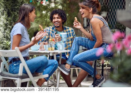 Cheerful friends enjoying snack at the bar's backyard on a beautiful weather. Quality friendship time together