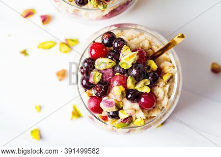 Overnight Oatmeal With Berries And Nuts In A Jar On A White Background. Healthy Breakfast Concept.