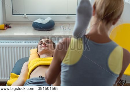 Physical therapist working on knee and leg of woman patient for remobilization