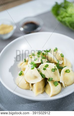Chinese Dumplings Jiaozi In The White Plate On The Gray Backrgound With Napa Chinese Cabbage And See