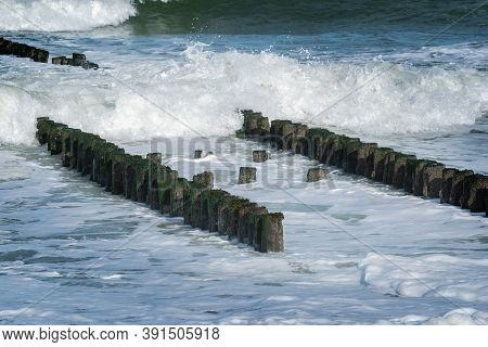Double Row Of Wooden Breakwater Poles Surrounded By Splashing Waves At The North Sea Coast At Westka