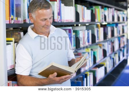 年配の男性人の本を持って図書館
