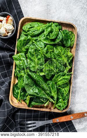 Young Spinach Leaves In A Wooden Bowl With Goat Cheese. Gray Background. Top View