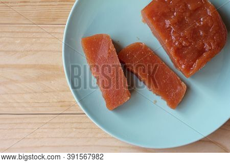 Top Down View Of Home Made Quince Paste: Dulce De Membrillo. Sliced On A Green Plate On A Wooden Tab