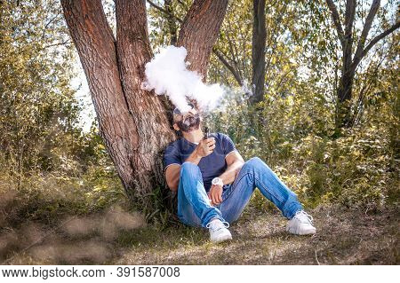 Stylish Man Smoke E-cigarette And Exhals Smoke Cloud. Vape.