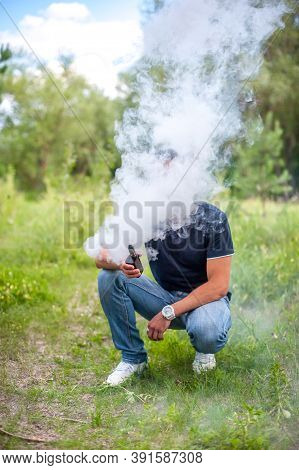 Stylish Brutal Man Enjoying An Electronic Cigarette Outside. The Man Smokes.