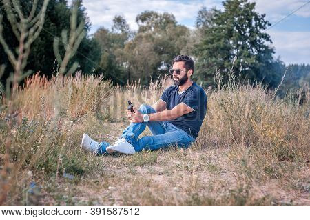 Bearded Vape Man Blows Up A Couple An Vape In The Calm Outdoors. Stylish Man.