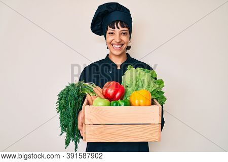 Beautiful brunettte woman chef holding fresh veggetables smiling with a happy and cool smile on face. showing teeth. 