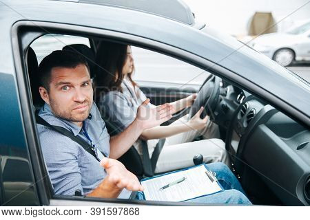 Male Driving Instructor Shrugs Up And Looks At Camera. Man Doesnt Understand What His Female Student