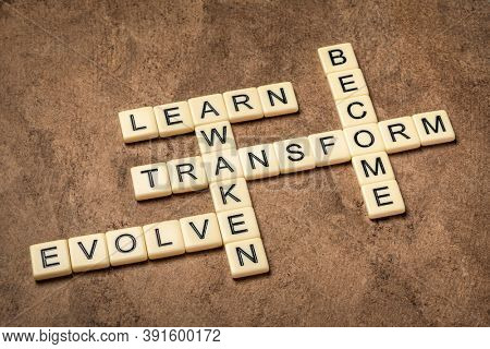 awaken, learn, evolve, transform and become crossword in ivory letter tiles against textured handmade paper, self improvement and personal development concept