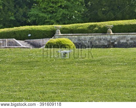 White Quadrocopter Flying Under Grass, Close-up. New Unmanned Aerial Copter. Electronics Innovation.