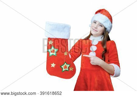 Beautiful Girl In Santa Clauss Hat And Red Dress Pointing Finger At Christmas Sock, Isolated On Whit