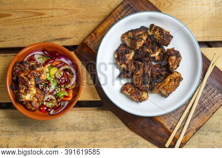 Plates Of Pan-asian Salad With Sesame Seeds And Grilled Chicken In Yakitori Sauce On Wooden Stands A