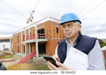 Gerente de construcción en obra con smartphone