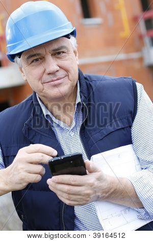 Empresario en obra con smartphone
