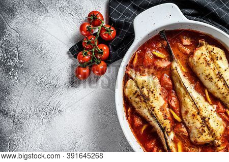 Monkfish Baked In Tomatoes In A Baking Dish. Black Background. Top View. Copy Space