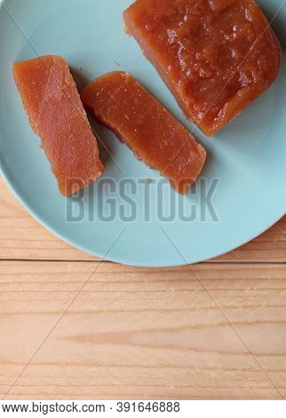 Top Down View Of Home Made Quince Paste: Dulce De Membrillo. Sliced On A Green Plate On A Wooden Tab