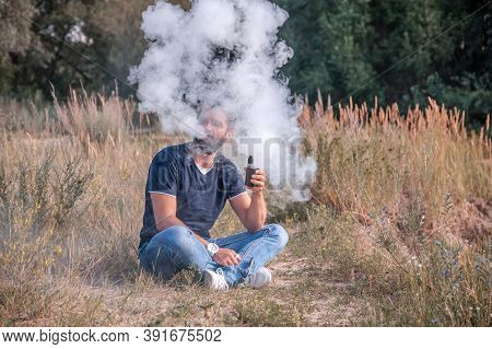 Brutal Man Exhales Cloud Of Smoke. Electronic Cigarette Concept.