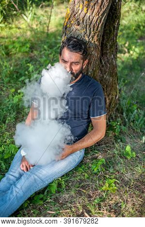 Bearded Man Smoking An Vape In Nature. Vaping Activity.