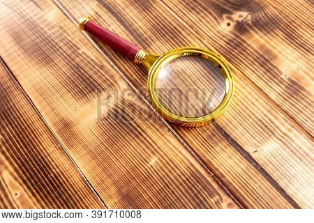 Close-up Of A Magnifier On A Wooden Table.