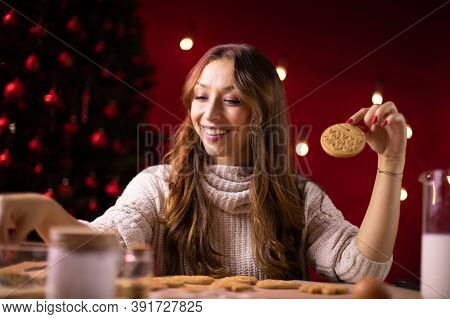 Christmas Bakery. Pretty Smiling Brunette Girl Making Christmas Gingerbread On Red Studio Background