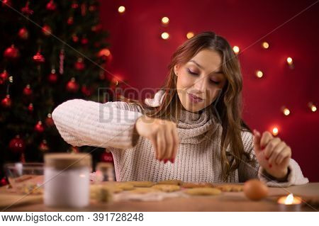 Christmas Bakery. Pretty Smiling Brunette Girl Decorating Freshly Baked Christmas Cookies With Chris