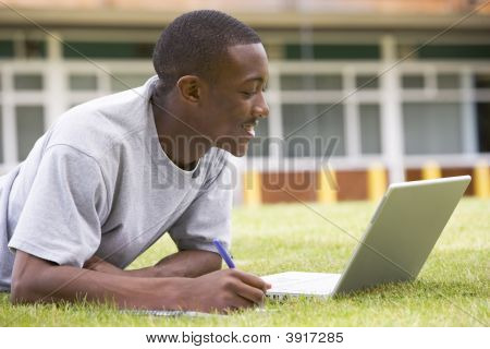 Studente sdraiato all'aperto sul prato con Laptop