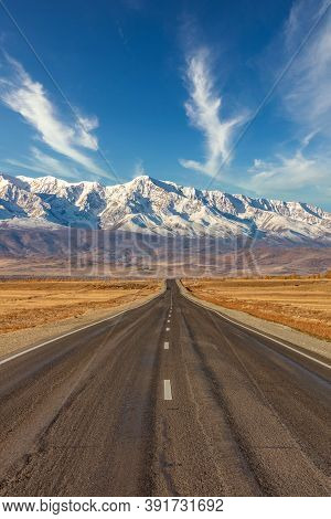 Portrait Size Shot Of A Straight Empty Highway Leading To The Snowy Peaks Of The Kuray Mountain Rang