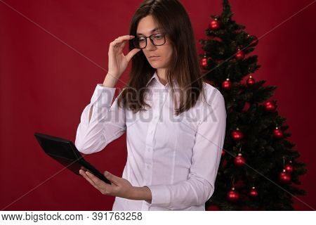 Thoughtful Brunette With Long Hair In Glasses Calculates New Year And Christmas Expenses On Calculat