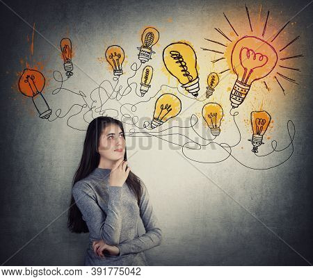 Creative Young Woman Thinking Of Great Ideas, Looking At Bright Lightbulb Sketches On The Wall. Smar