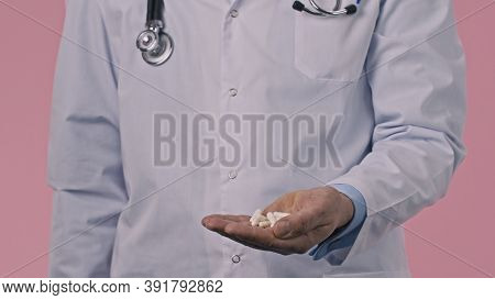 Close Up View Of Male Doctor In Medical Uniform Pouring Pills Down And Holding Them In Palm Of Hand 