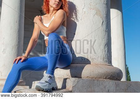 Red-haired Woman Athlete, Thirty-six Years Old, In Sports Leggings, Sits On The Street, Demonstratin
